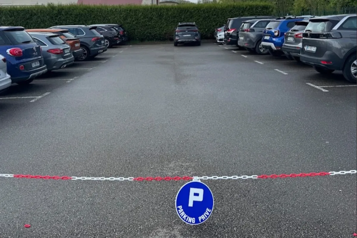 Le parking extérieur privé GoPark 60000, avec des véhicules stationnés derrière une chaîne et un panneau « Parking privé »